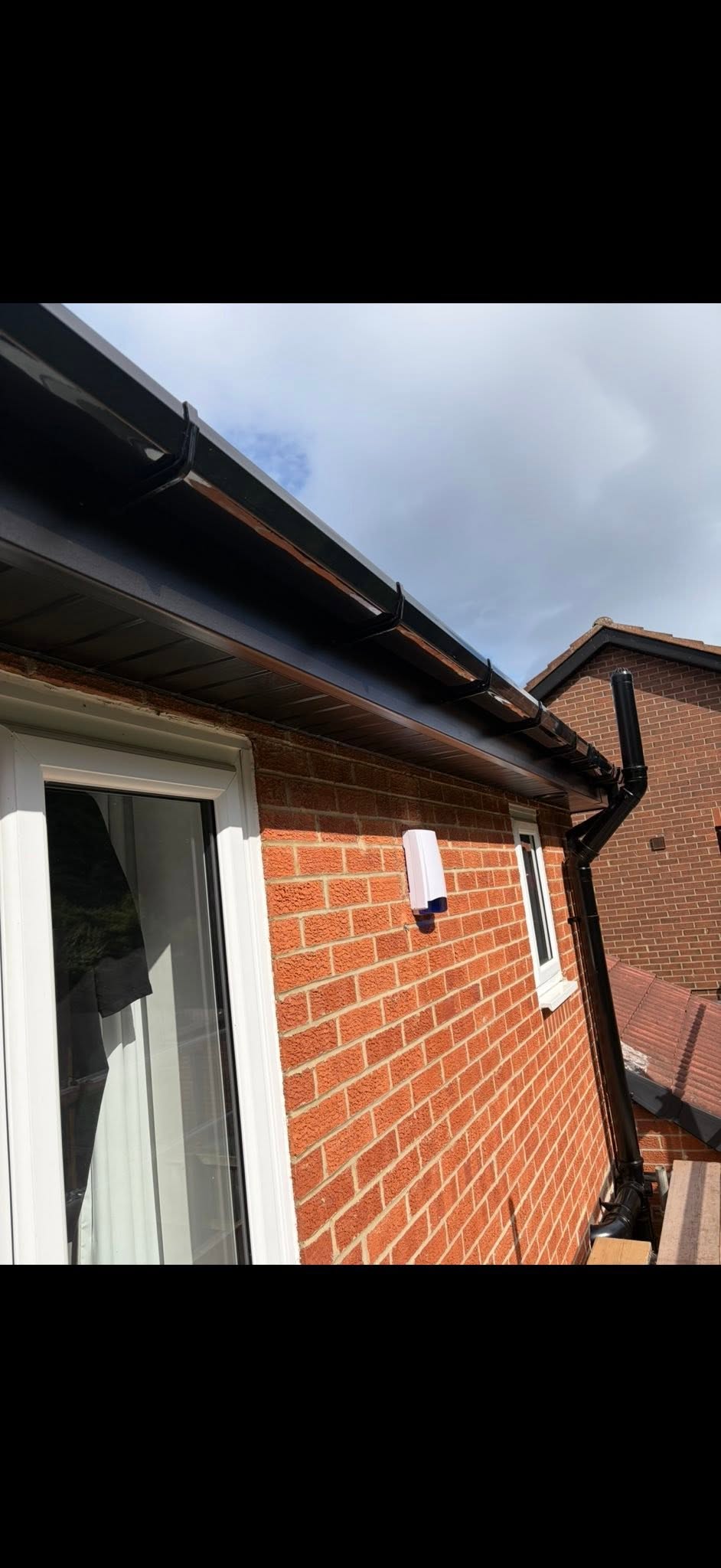 Black uPVC fascia and soffit installation on a brick property